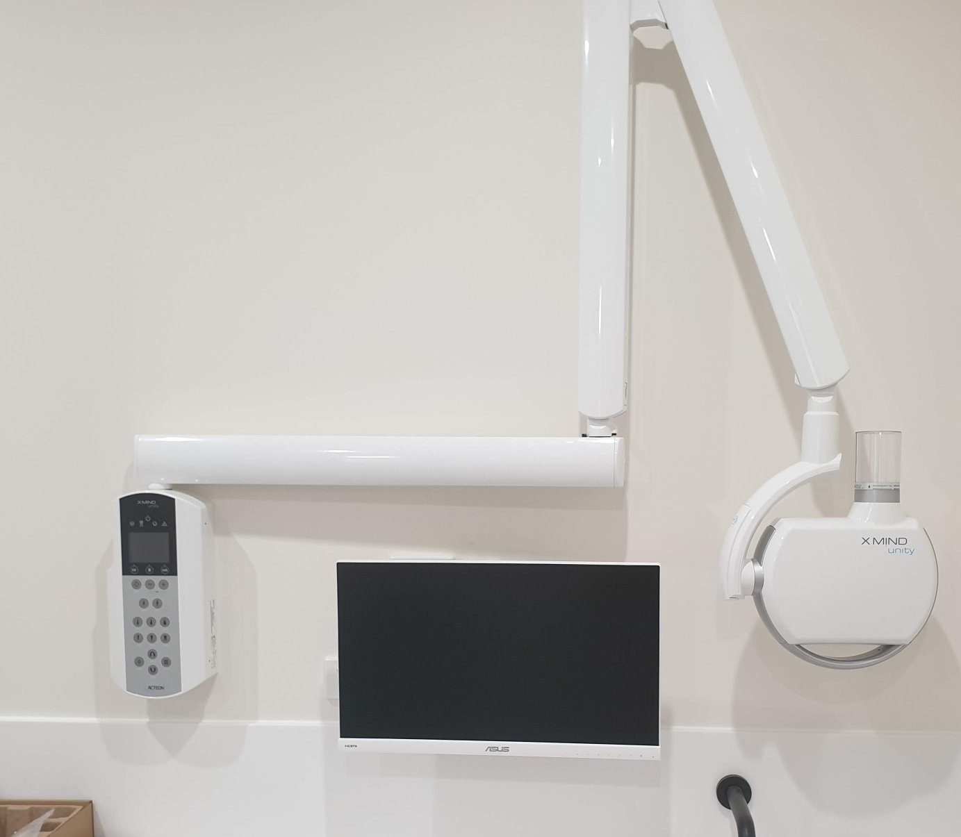 Clean dental surgery technology installation with wall-mounted imaging equipment and integrated monitor cabling.